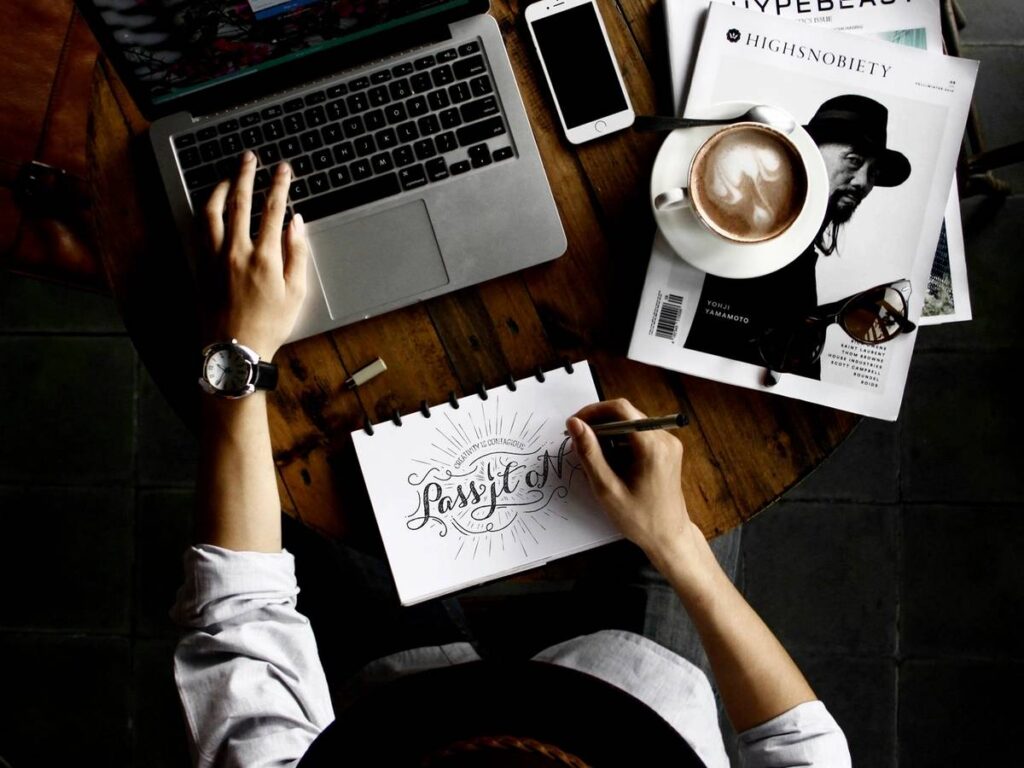 People collaborating over notes and laptops at a cozy cafe table.