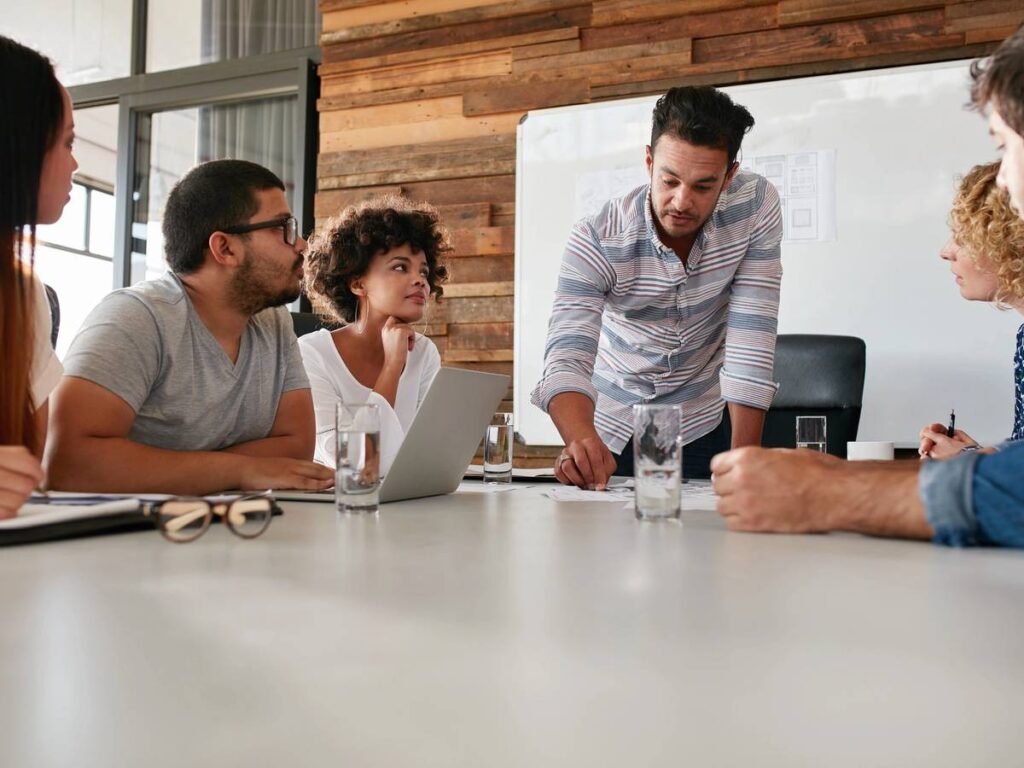 People collaborating over notes and laptops at a cozy cafe table.