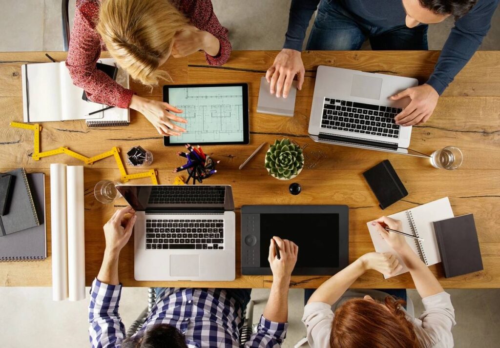People collaborating over notes and laptops at a cozy cafe table.