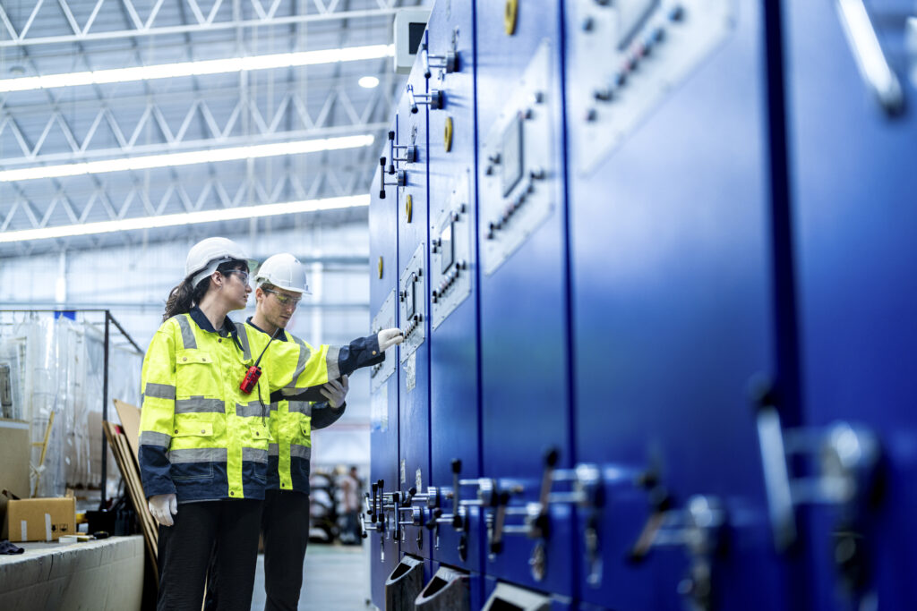 Two engineers inspecting electrical control panels in a facility.