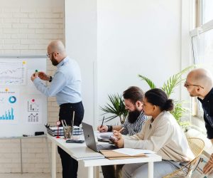 A man presenting to colleagues in a modern office meeting.