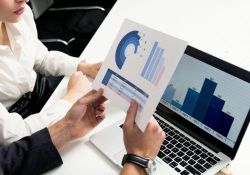 Team analyzing financial charts on paper and laptop