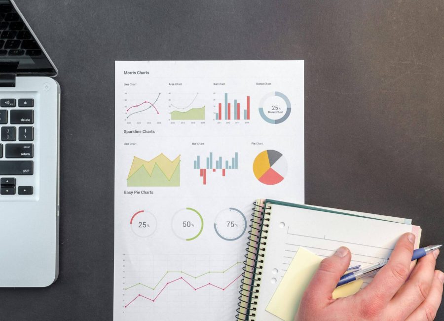 Overhead view of a business desk with charts and a laptop, ideal for data analysis concepts.