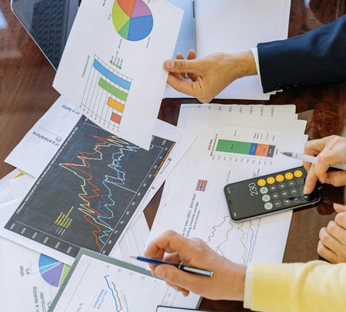 People analyzing financial charts and graphs with a calculator.